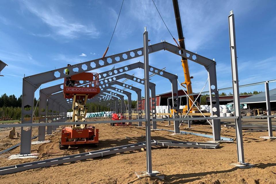 Steel portal frames being erected with crane and work platform, Kurikka